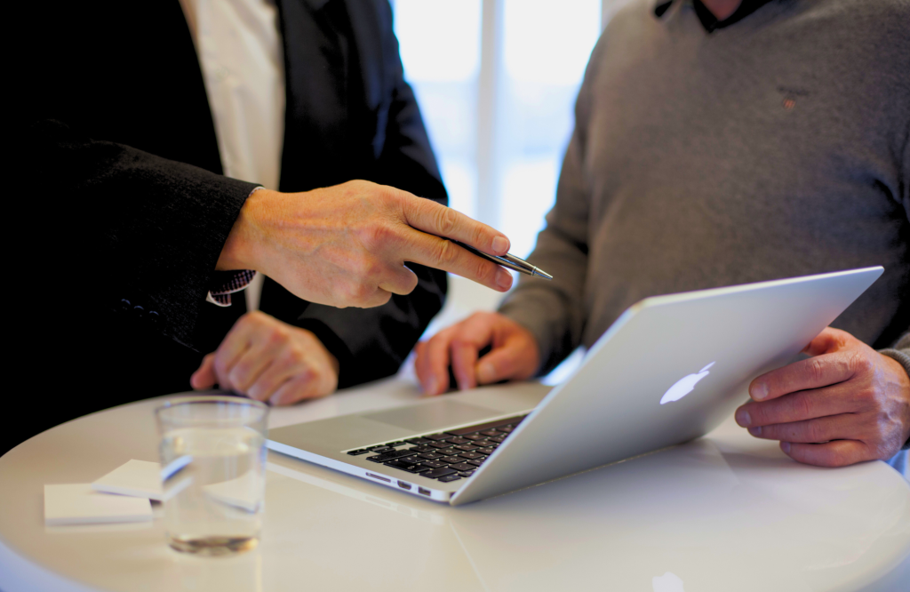 Er worden twee mensen en een laptop afgebeeld waarvan een persoon advies geeft over ERP-software